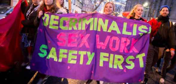 Sex workers and allies hold a banner reading: Decriminalise sex work, safety first