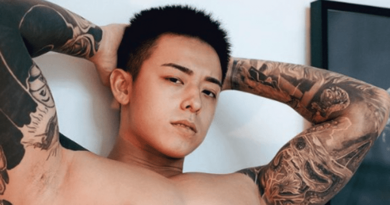 Titus Low, topless, with his hands behind his head