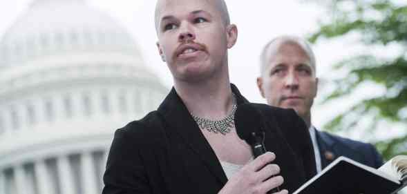 Sam Brinton wearing a woman's suit jacket with necklace speaks outside the US capitol