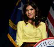 Kristi Noem, the governor of South Dakota, is wearing a yellow outfit while standing at a podium