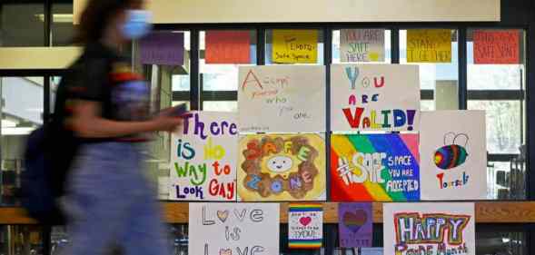 Several LGBT+ posters celebrating Pride month are posted on a glass partition in a high school
