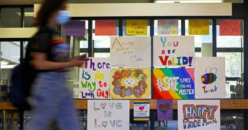 Several LGBT+ posters celebrating Pride month are posted on a glass partition in a high school