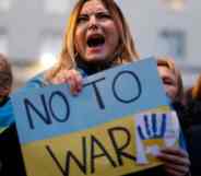 A person holds a sign that reads "No to war" that is in the colours of Ukraine's flag to protest Russia's invasion of the country