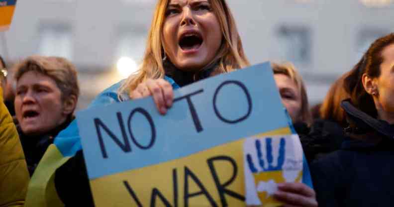 A person holds a sign that reads "No to war" that is in the colours of Ukraine's flag to protest Russia's invasion of the country