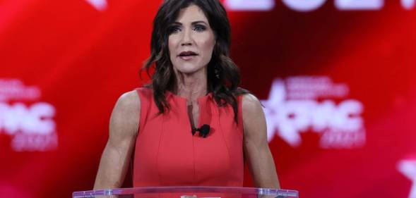 South Dakota governor Kristi Noem wears a red outfit as she speaks on stage