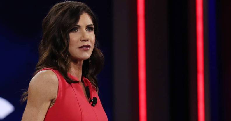 South Dakota governor Kristi Noem wears a red outfits as she stands at a podium
