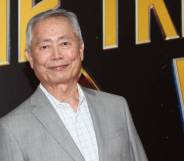 George Takei, an Japanese-American actor, looks at the camera while wearing a white shirt and grey jacket