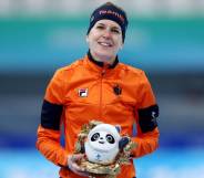 Ireen Wüst, an Olympic speed skater, poses with a panda mascot for the Beijing Olympics while wearing an orange jacket