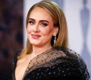Adele, a white woman, wears a black dress during an appearance at the 2022 BRIT Awards