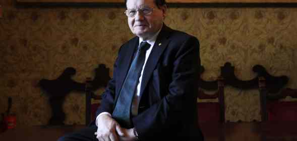 HIV co-discoverer professor Luc Montagnier poses on a chair in a suit