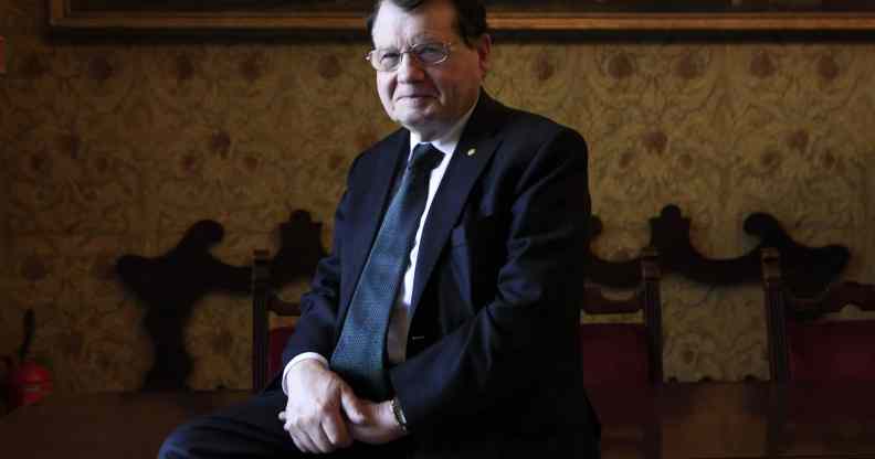 HIV co-discoverer professor Luc Montagnier poses on a chair in a suit