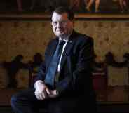 HIV co-discoverer professor Luc Montagnier poses on a chair in a suit