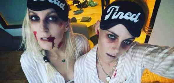 Dylan Meyer and Kristen Stewart dress up as zombies with pale complexions and fake blood while wearing eye masks that read 'dead tired'