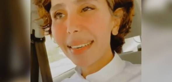 Maha al-Mutairi, a trans woman, wears a white shirt while sitting down