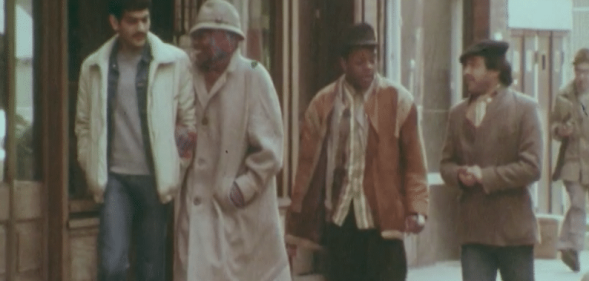 Four Black men walking a street in the 80s
