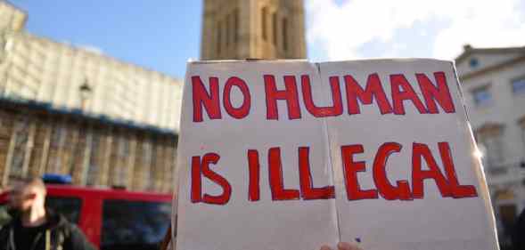 A protester holds a placard saying No Human Is Illegal