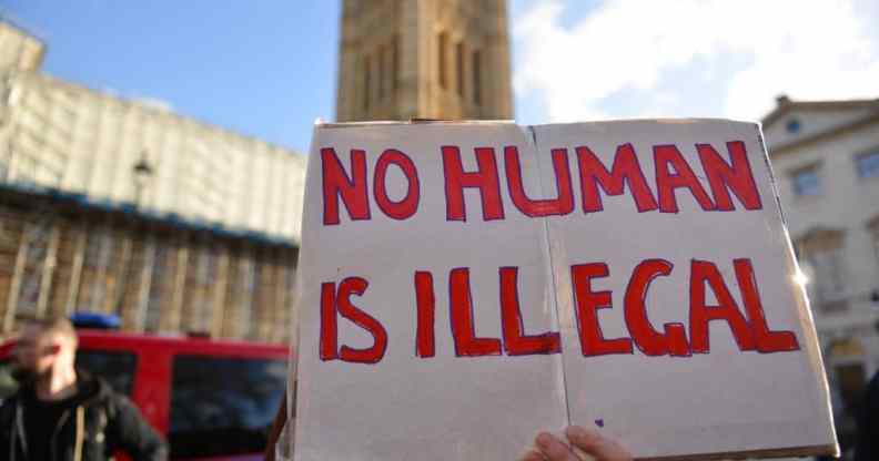 A protester holds a placard saying No Human Is Illegal