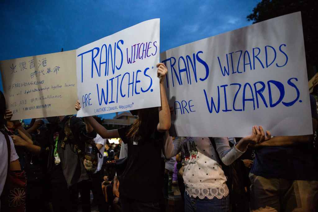 Protesters hold signs calling out JK. Rowling's twitter comments