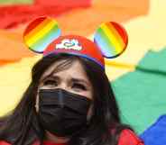 A woman wears Mickey Mouse ears with the Pride colours