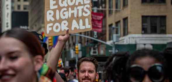 A participant is seen holding a sign reading "Equal rights for all" at a LGBT+ march
