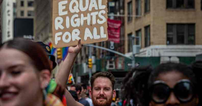 A participant is seen holding a sign reading "Equal rights for all" at a LGBT+ march