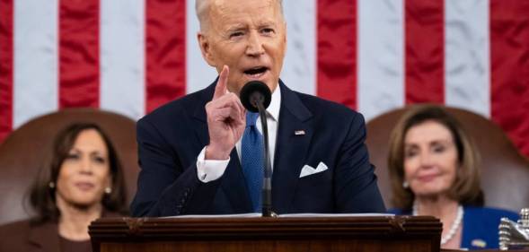 President Joe Biden stands at a podium to deliver his State of the Union address with an American flag in the background