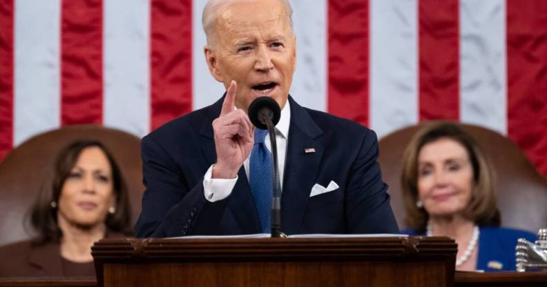 President Joe Biden stands at a podium to deliver his State of the Union address with an American flag in the background