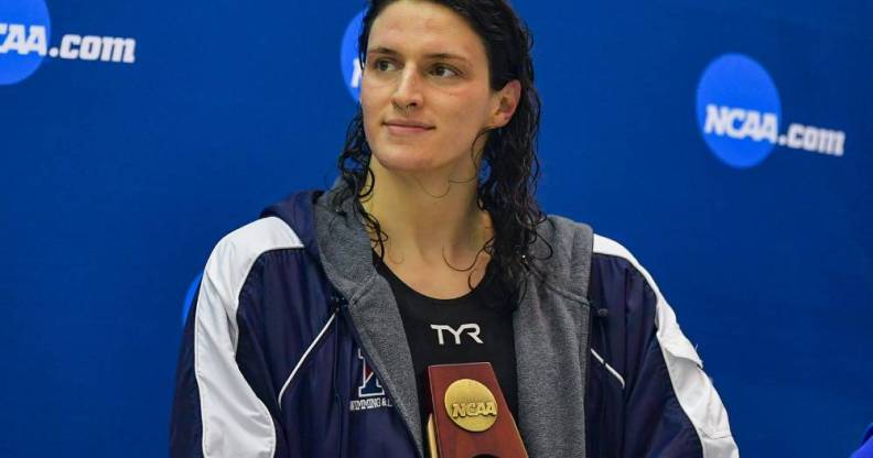 University of Pennsylvania swimmer Lia Thomas holds an NCAA trophy while she looks off to the side