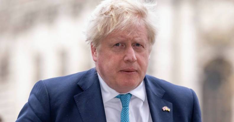 UK Prime Minister Boris Johnson is seen wearing a white shirt, light blue tie and darker blue suit jacket while walking outside
