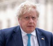 UK Prime Minister Boris Johnson is seen wearing a white shirt, light blue tie and darker blue suit jacket while walking outside