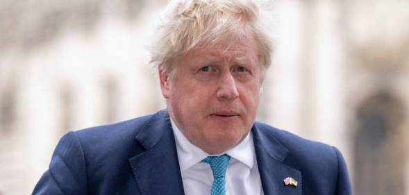 UK Prime Minister Boris Johnson is seen wearing a white shirt, light blue tie and darker blue suit jacket while walking outside