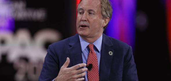 Texas attorney general Ken Paxton is seen wearing a light blue shirt, red tie and darker blue suit jacket