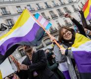 Activists hold up non-binary flags as they protests during the march in support of trans people