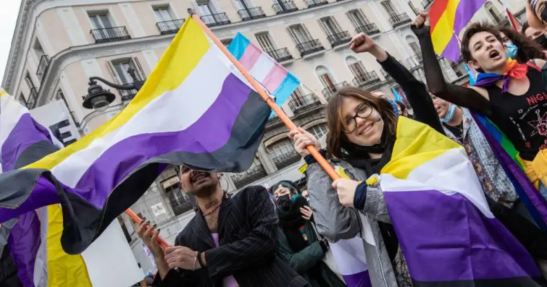 Activists hold up non-binary flags as they protests during the march in support of trans people