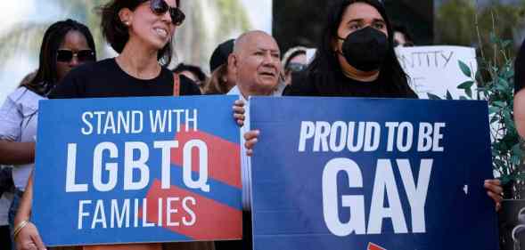 Two people hold signs reading "Stand with LGBTQ families" and "Proud to be gay" as they protest the passage of Florida's "Don't Say Gay" bill