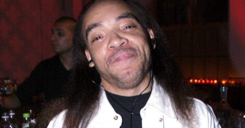Kidd Creole, a rapper, smiles at the camera while wearing a black top and white jacket