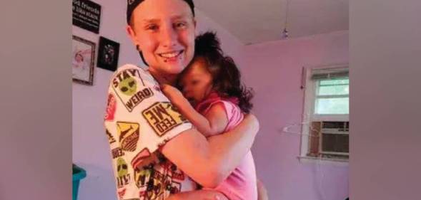 Matthew Angelo Spampinato, a white trans man, is seen holding a small child