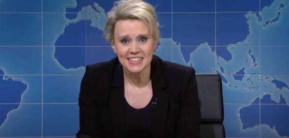 Kate McKinnon, a cast member of Saturday Night Live, wears a black outfit as she appears in front of a fake news desk set up on the show's Weekend Update segment