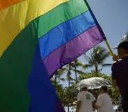A person holds an LGBT+ flag as they participate in a march celebrating Honolulu Pride Month in Hawaii