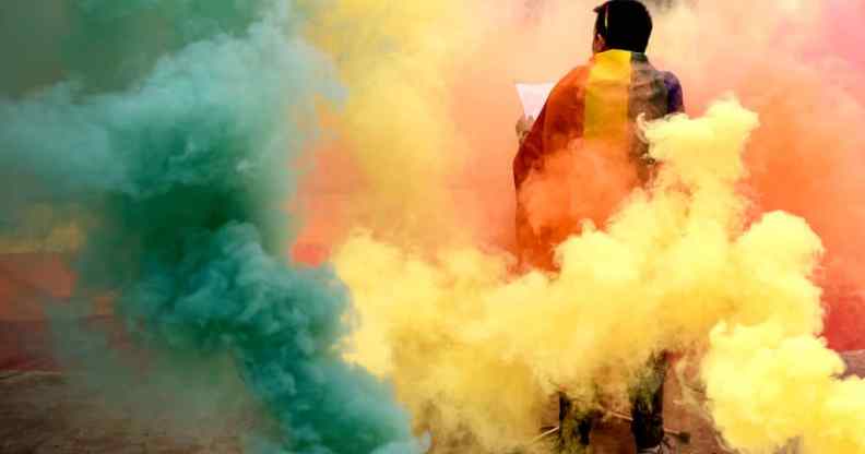 A person stands among multicoloured smoke