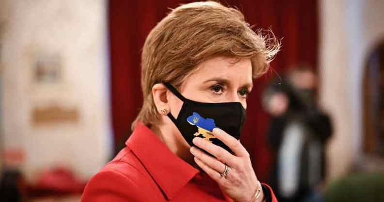 Scotland's first minister Nicola Sturgeon wearing a red jacket and a black face mask
