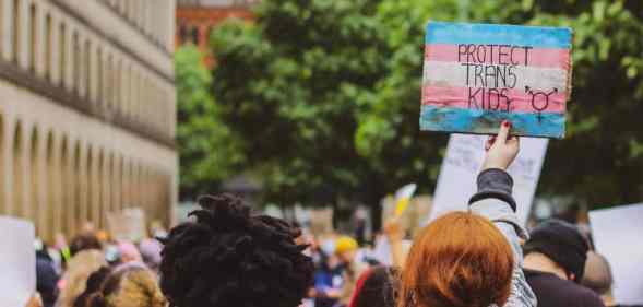 Person holds a sign that reads "Protect trans kids"