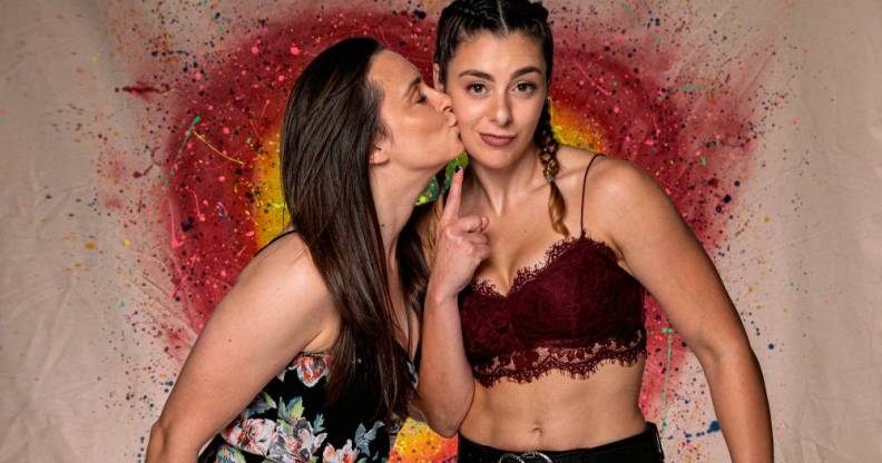PROGRESS Wrestling stars Jetta and Charlie Morgan, a British LGBT+ couple and wrestlers, hold each other close with a rainbow heart in the background