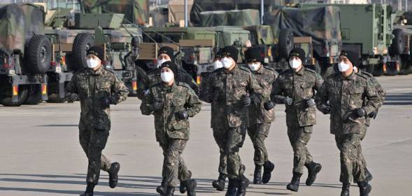 Cadets in the South Korean military job in front of military equipment