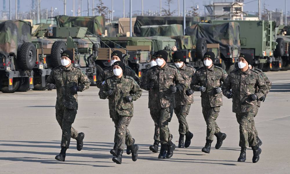 Cadets in the South Korean military job in front of military equipment