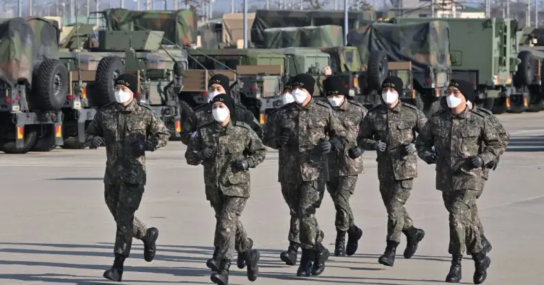 Cadets in the South Korean military job in front of military equipment