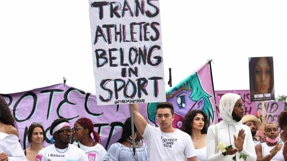 A person holds up a sign that reads "Trans athletes belong in sports" during a demonstration
