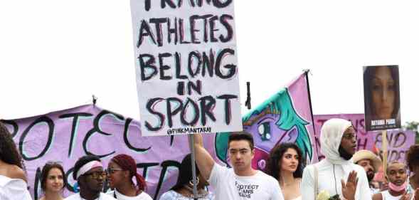 A person holds up a sign that reads "Trans athletes belong in sports" during a demonstration