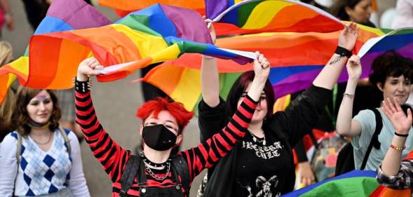 People hold up LGBT+ rainbow flags during a march in Scotland