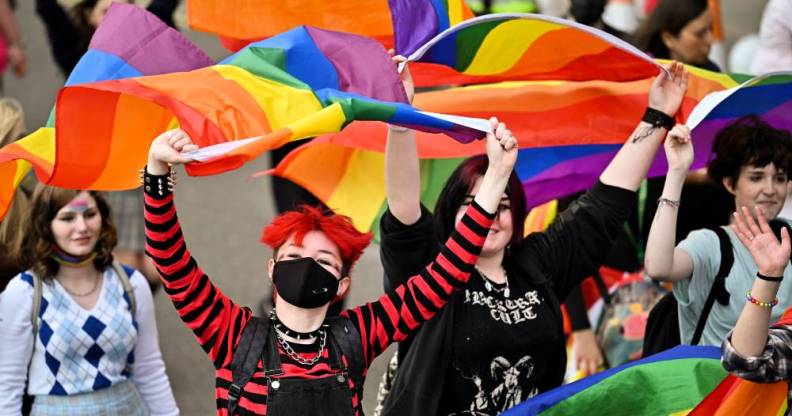 People hold up LGBT+ rainbow flags during a march in Scotland